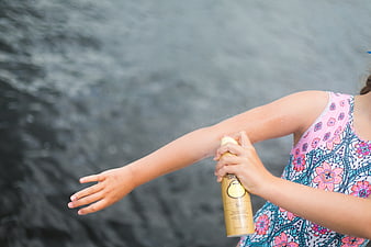 Girl Applying Sunscreen Spray by Lake