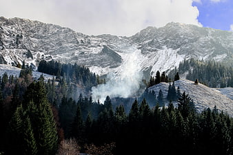 Snowy Mountain Peaks with Misty Forest Valley