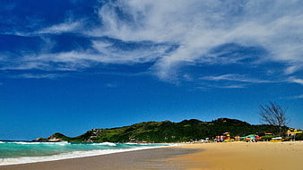 Sunny Beach with Green Hills and Blue Sky