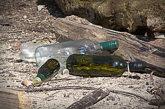 Discarded Glass Bottles and Plastic Waste on a Sandy Beach