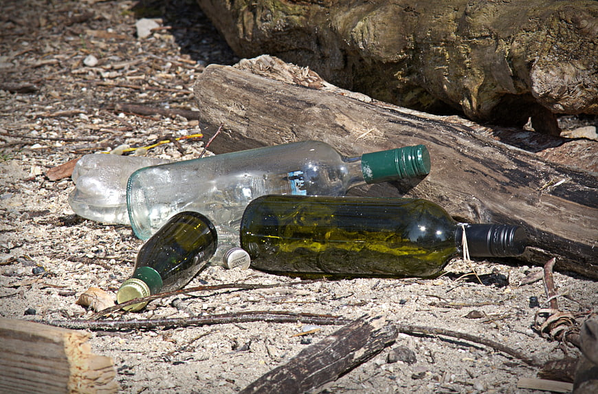 Discarded Glass Bottles and Plastic Waste on a Sandy Beach