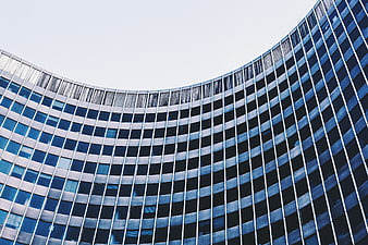 Curved modern glass office building facade with blue windows