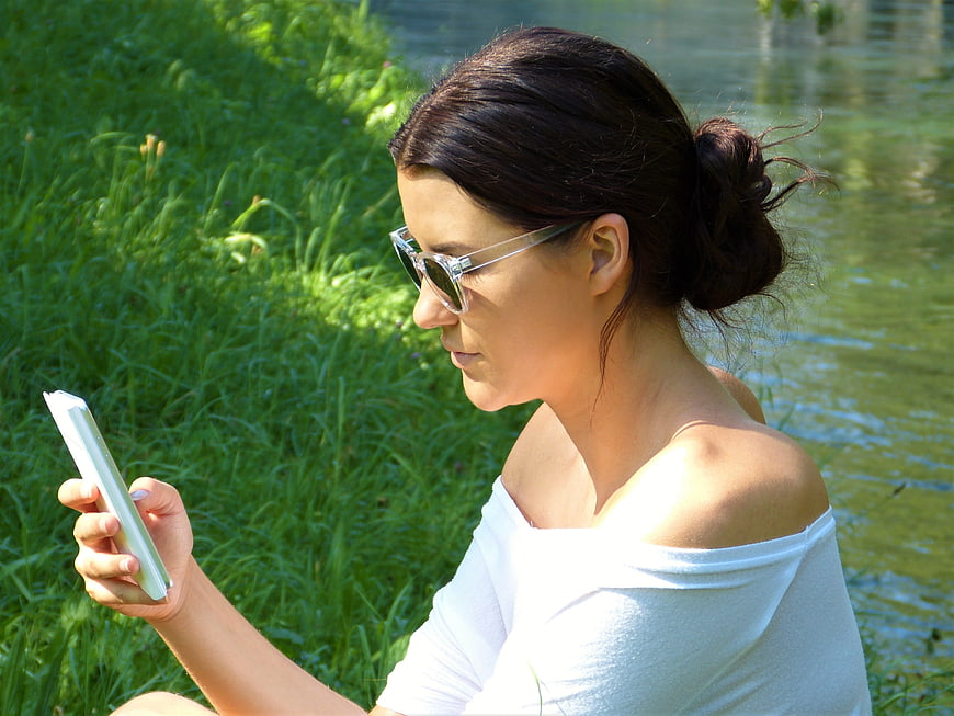 Young Woman Using Smartphone Outdoors by Lake