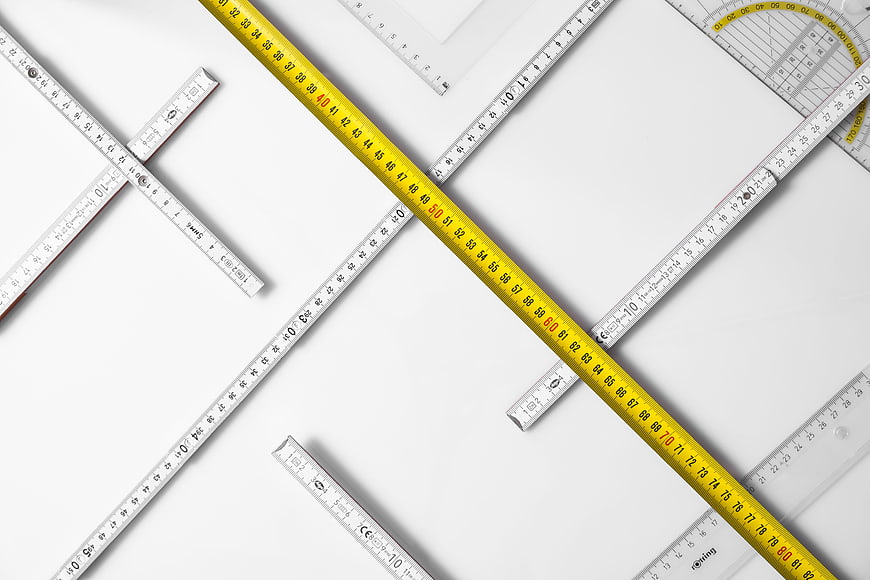 Flat lay of yellow tape measure and rulers on white background