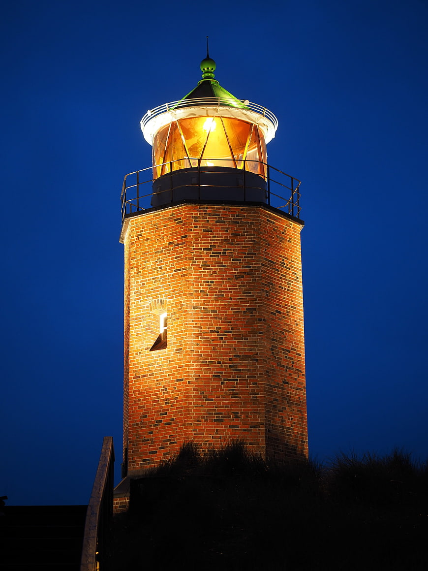 Illuminated Brick Lighthouse Tower Against Deep Blue Night Sky