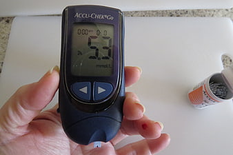 Hand holding Accu-Chek Go blood glucose meter with test strip