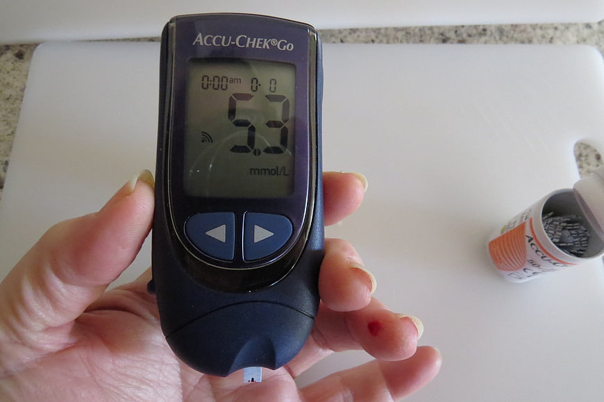 Hand holding Accu-Chek Go blood glucose meter with test strip
