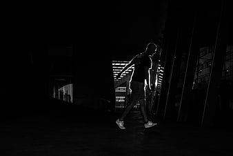 Silhouette of man walking in dark urban night scene