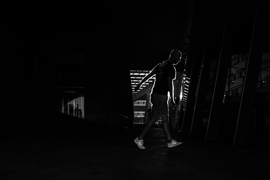 Silhouette of man walking in dark urban night scene