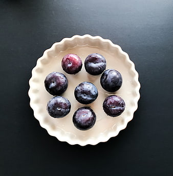 Fresh Plums in White Tart Pan on Black Background