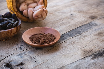 Cocoa powder, cacao beans, and fresh pods on rustic wood