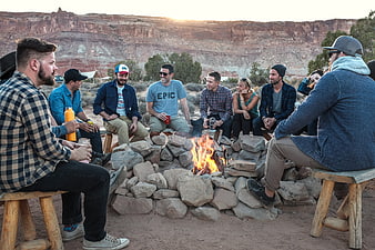 Group of friends laughing around a campfire in a desert landscape