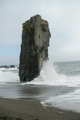 Tall Sea Stack Rock Formation on Overcast Beach