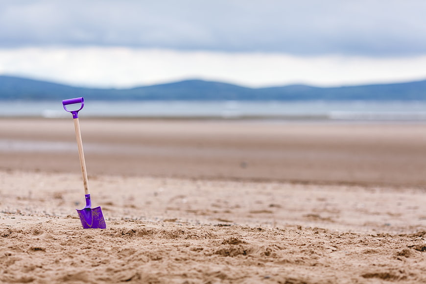 Purple Toy Shovel Stuck in Sand on Beach