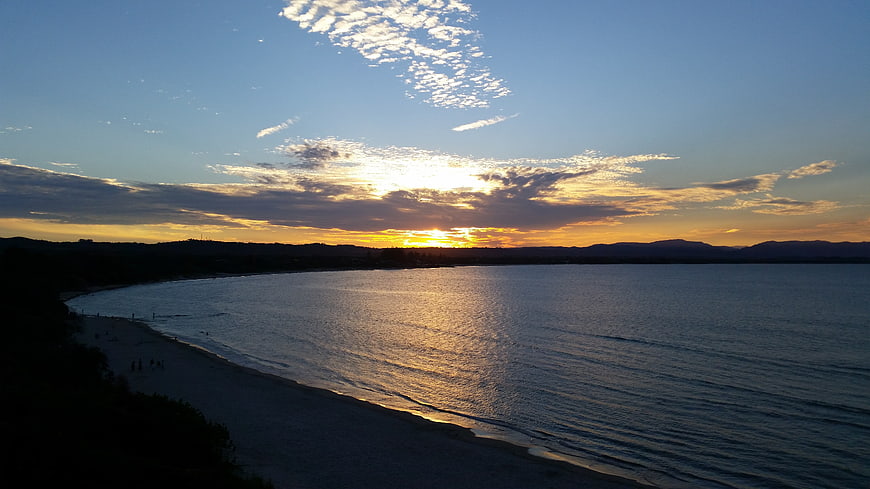 Golden Sunset Over Calm Ocean Bay With Silhouetted Hills