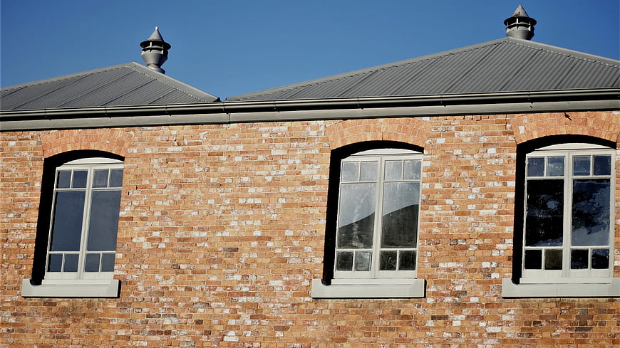 Red Brick Building Facade with Arched Windows and Blue Sky
