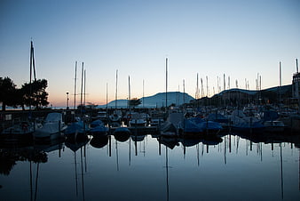 Silhouetted Sailboats in Harbor at Dusk with Mountain Reflection