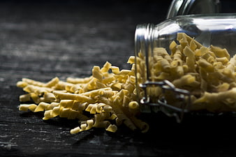 Spilled Fusilli Pasta from Glass Jar on Dark Wood