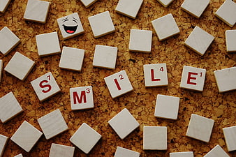 Scrabble tiles spelling smile on cork board background