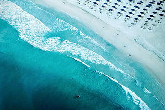 Aerial view of turquoise ocean waves crashing on white sandy beach