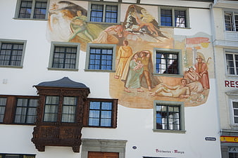 Historic building facade with mural and bay window in St. Gallen