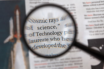 Magnifying glass focusing on science and technology text in a newspaper