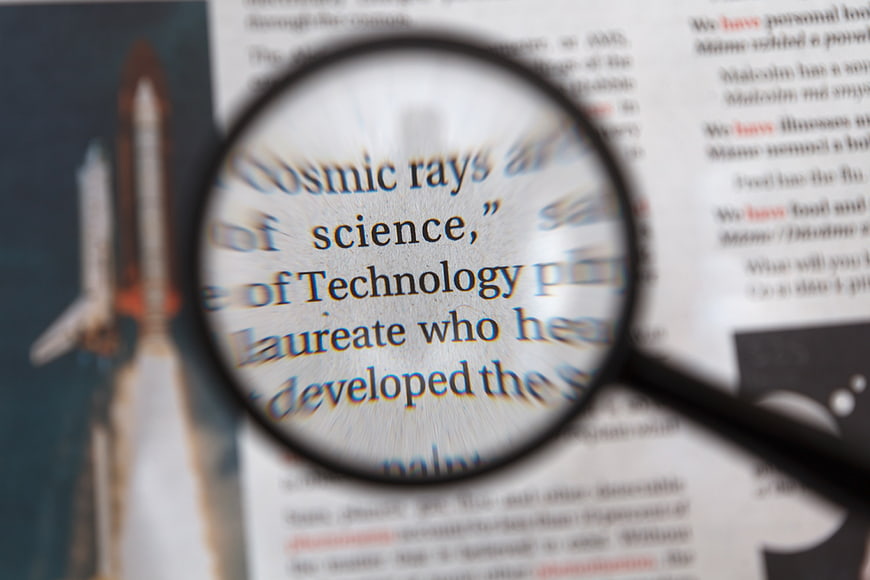 Magnifying glass focusing on science and technology text in a newspaper