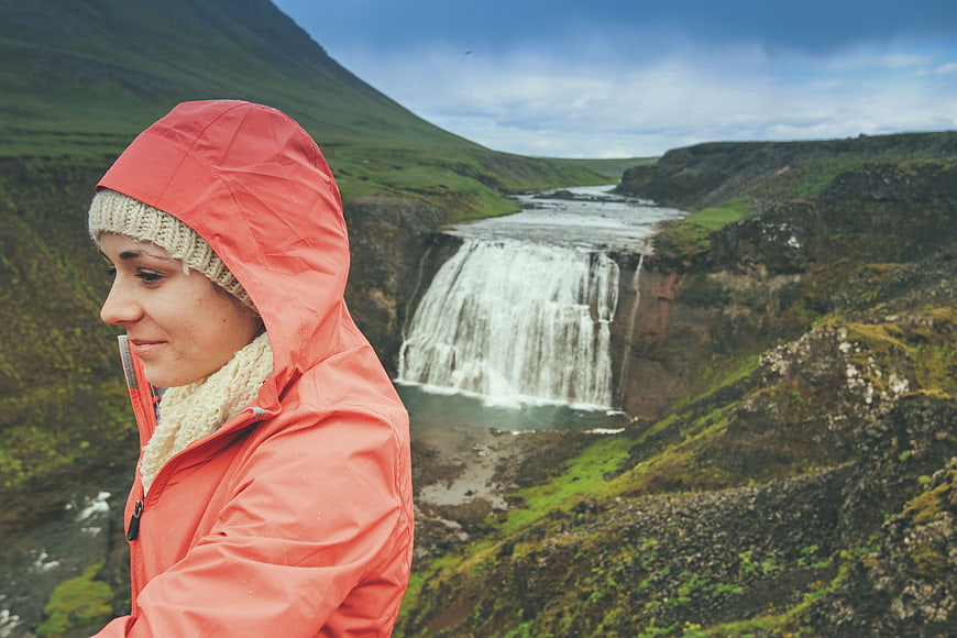 Woman in Orange Raincoat Viewing Waterfall in Nature