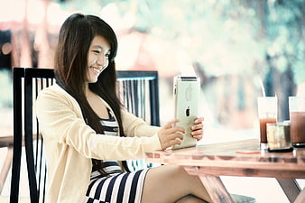 Smiling Young Woman Using Tablet at Outdoor Cafe