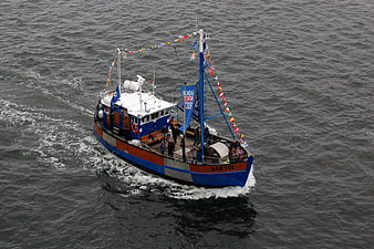 Aerial view of blue and wooden fishing boat sailing on gray sea