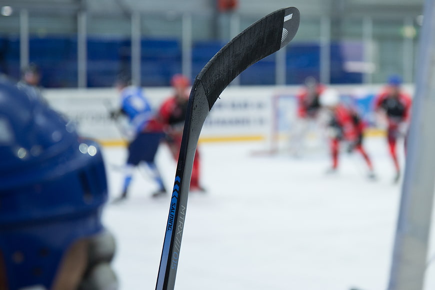 Close-up of hockey stick with blurred game action in background